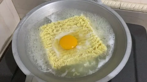 Cook instant noodle with an egg on top in boiling water Stock Footage 282894669