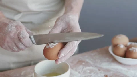 A cook in the kitchen breaks an egg and separates the yolks from the whites. Vídeos de archivo 301287810