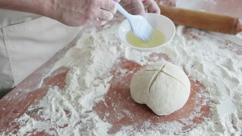 The cook in the kitchen coats the dough with egg white and cooks the bread. Stock Footage 301600032