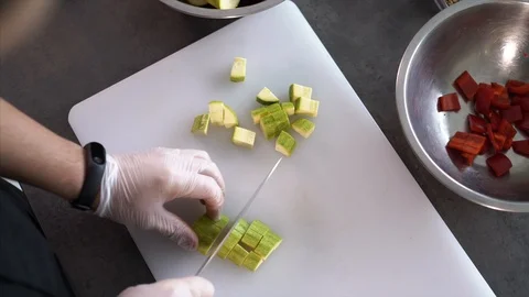 A cook in the kitchen cuts a zucchini. Dice the zucchini. Vegetables. Vegan Stock Footage 126445292