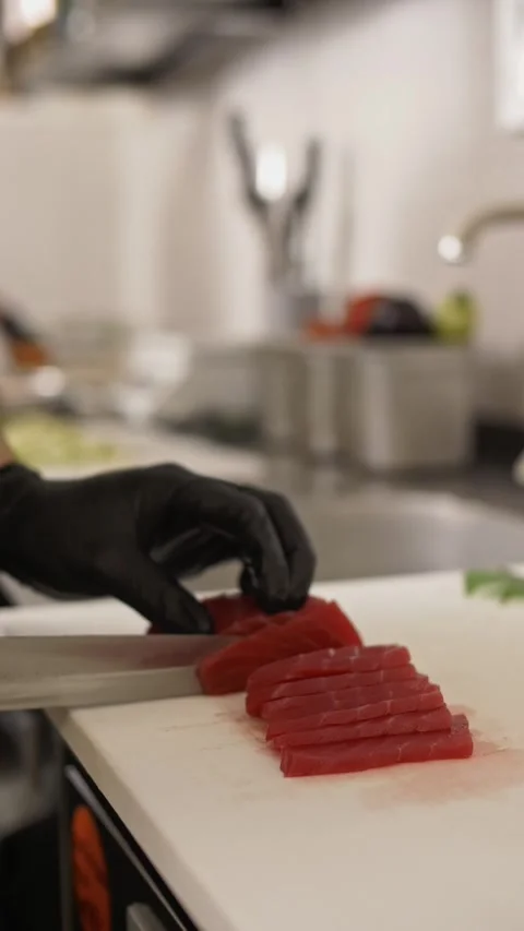 The cook in the kitchen is cutting pieces of red fish with a sharp knife Stock Footage 282784302