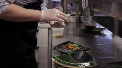 The cook in the kitchen decorates the dish with greens in a plate. Stock Footage 76808486