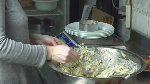 The cook in the kitchen distributes the dish on plates and weighs the weight in Vídeo Stock 102940205