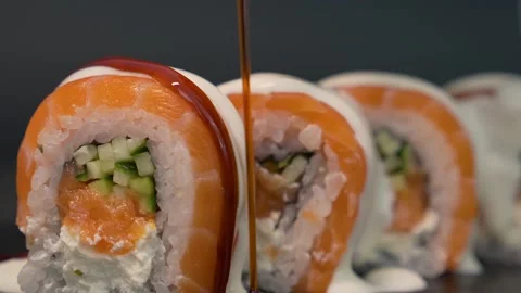 Cook in the kitchen generously and appetizingly pours the sushi roll with unagi  Stock Footage 156967006