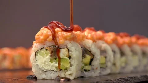 Cook in the kitchen generously and appetizingly pours the sushi roll with unagi  Stock Footage 156967074