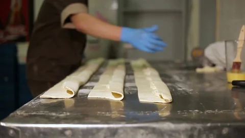 Cook in the kitchen greases the dough with egg Stock Footage 106475823