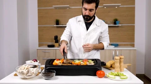 Cook in kitchen grilling meat and vegetables Stock Footage 85380607