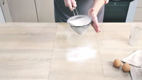 Cook in kitchen pours wheat flour into metal strainer and sift 스톡 동영상 140469333