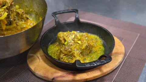 Cook in kitchen prepares dish spicy in cast iron pan on wooden board on table. Video stock 267284622