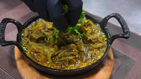 Cook in kitchen prepares dish spicy in cast iron pan on wooden board on table. Stock Footage 267285031