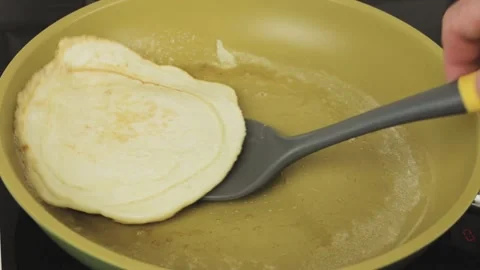 A cook with a kitchen spatula turns the pancake over in the pan  Stock Footage 147172001