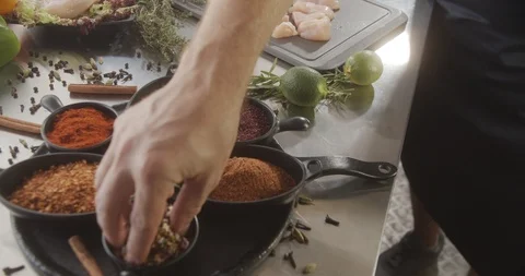 Cook in the kitchen takes pinch of spices and sprinkles on fresh chicken breast Stock Footage 123764324