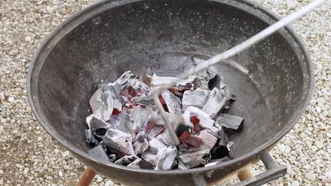 The cook lights the coals in the grill to cook food. Stock Footage 294298928