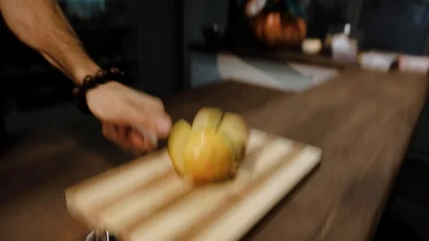Cook lowers sharp knife cutting yellow apple into pieces 스톡 동영상 120664490