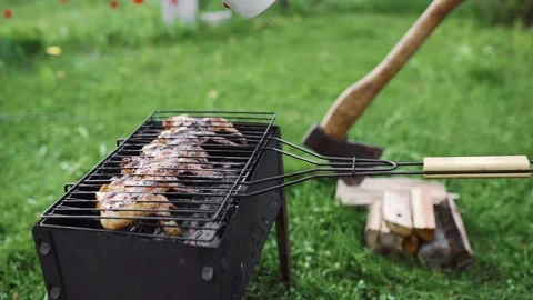 The cook makes BBQ on the hot coals of the grill outdoors and adds sauce to the Video stock 89744390