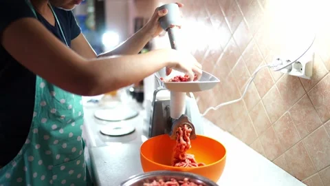 Cook makes minced meat by pushing the meat with a pusher into an electric meat Stock Footage 278685546