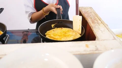 The cook makes an omelette of eggs in two pans, flips, fries on both sides. HD Stock Footage 96121647