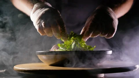 The cook makes a salad against the backdrop of smoke. Stock Footage 193996979