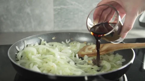 The cook makes vegetable dish with onion fried in balsamic vinegar and adds Stock Footage 74065953