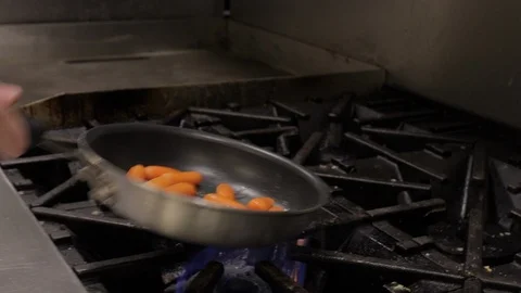 Cook making carrots over the fire on a pan Stock Footage 125411680