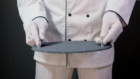Cook man hold empty tray on black backgrouind. Stock Photos