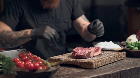 Cook man preparing steak and sprinkle salt on the both side of the meat. Slowmot Stock Footage 151469841