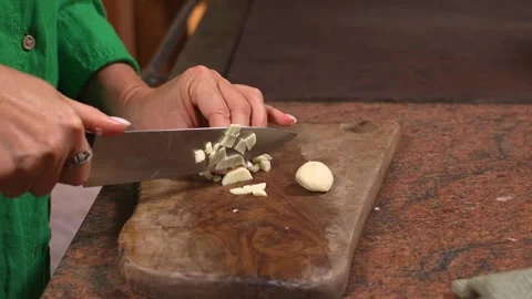 Cook Mincing Garlic with a Knife at a Rustic Kitchen Counter Stock Footage 346180158