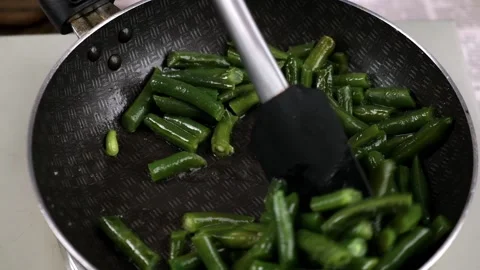 The cook mixes stewed green string beans in a frying pan with spatula. close-up. Stock Footage