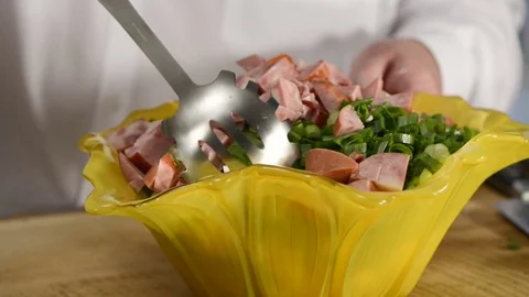 The cook mixes vegetables and ham salad in beautiful ware Stock Footage 79348285