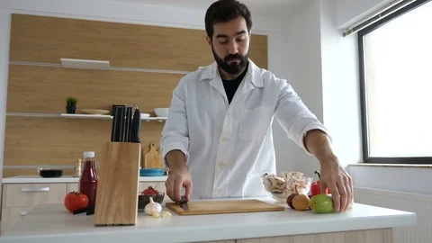 Cook in modern kitchen cutting a squash on wooden table Stock Footage 85322686