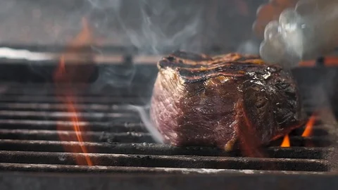 Cook moves the meat on the grill. Lots of fire. Slow motion, close-up Stock Footage