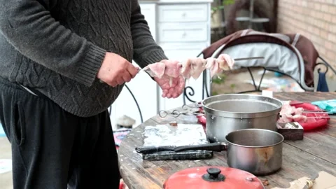 The cook in the open air, in the street puts meat on a skewer Stock Footage 130968360