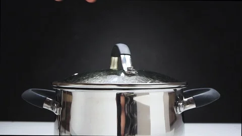 The cook opens the lid of the pan. The pan is on the stove. Steam comes from the Video stock 89840294