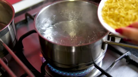 Cook pasta Male chef adding penne pasta into boiling water in pot. Stock Footage 291143392