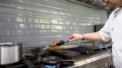 Cook placing a piece of grilled beef meat from the grill to a pan Stock-Footage 95889042