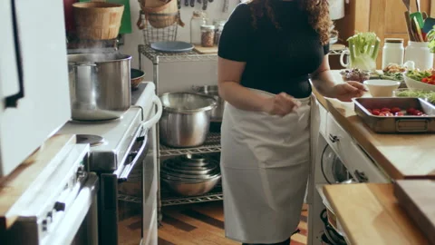 Cook placing tomatoes in oven in a large kitchen with an array of a equipment an Stock Footage 199460614