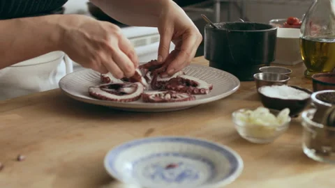 Cook plating octopus on a plate for an octopus carpaccio dish in a large well ap Stock Footage 199459048