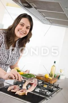 Cook - plus size woman grill fish in kitchen Stock Photos