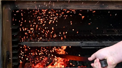 Cook with a poker stirs the coals in the oven Stock Footage 125889853