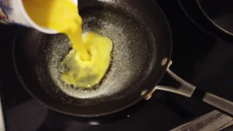 Cook Pour eggs in Omelet Pan close up poured from cup Stock Footage 228898628