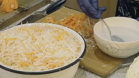 The cook pours brine into chopped cabbage and carrots Stock Footage 274432227
