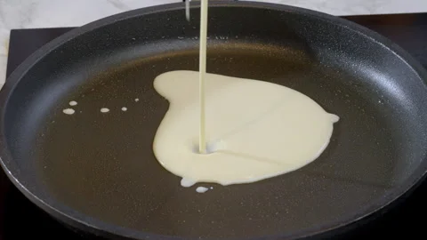 Cook pours liquid pancake batter into hot pan. Slow motion footage 100fps. Stock Footage 308181279