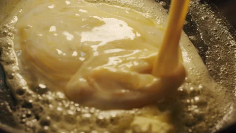 The cook pours mixed eggs and cream into a frying pan with butter Video stock 152649327