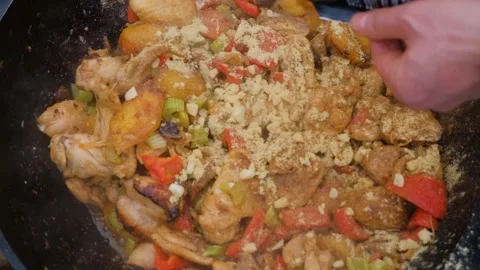 The cook pours spices into the dish. Adding spices when cooking. Spices are Stock Footage 278868533
