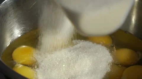 Cook pours sugar into a container with chicken eggs Stock Footage 148315532
