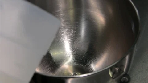 The cook pours a white preform, ice cream, cream into a large metal bowl. Mixer Stock Footage 74869060