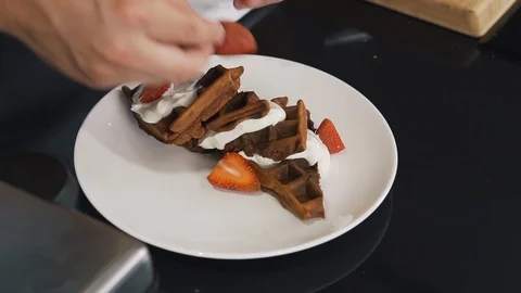 Cook prepared Belgian waffles, crispy dessert, cut into halves, spread on plate Stock Footage 123353850
