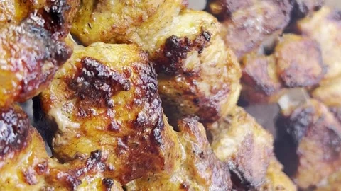 The cook prepares barbecue from pork meat. The barbecue is spinning on an open Stock-Footage 250352355
