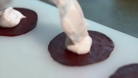 Cook prepares beetroot appetizer. Сook puts cream cheese on slices of beetroot Stock Footage 126447018