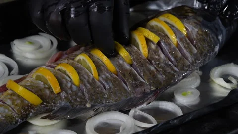Cook prepares carp fish with lemon on baking tray for baking in the oven Stock Footage 303000978